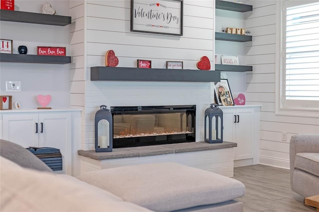 interior space with wooden walls, a large fireplace, and light hardwood / wood-style floors