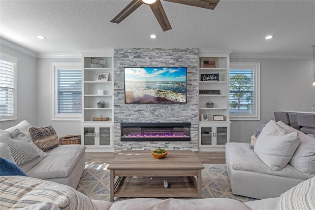 living room with crown molding, ceiling fan, hardwood / wood-style floors, a fireplace, and a textured ceiling