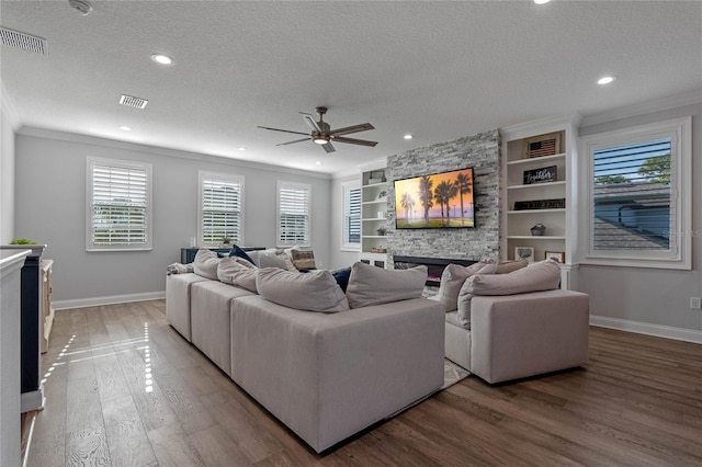 living room with hardwood / wood-style flooring, a fireplace, ornamental molding, and a textured ceiling