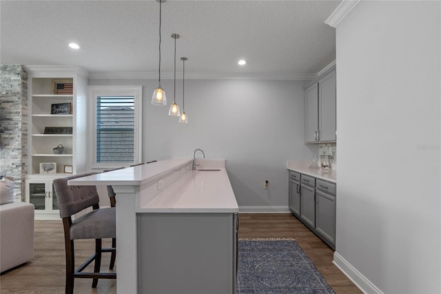 kitchen with a breakfast bar, sink, hanging light fixtures, and gray cabinetry