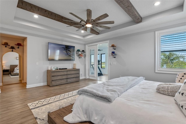 bedroom with light hardwood / wood-style flooring, ceiling fan, access to exterior, a textured ceiling, and a raised ceiling