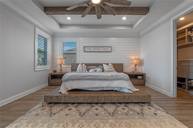 bedroom with wood-type flooring, a spacious closet, ceiling fan, and a tray ceiling