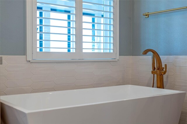 bathroom featuring tile walls and a tub