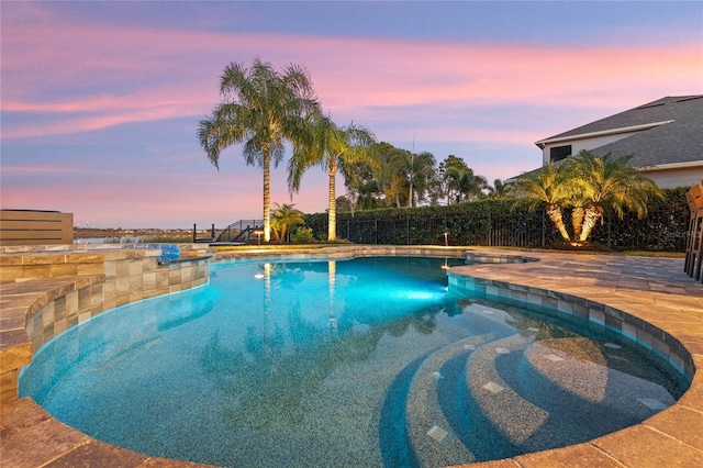 pool at dusk with a patio area