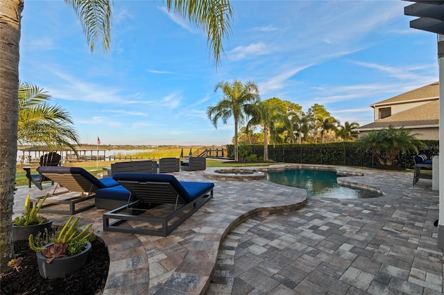 view of pool with an outdoor fire pit, a patio, a water view, and an in ground hot tub