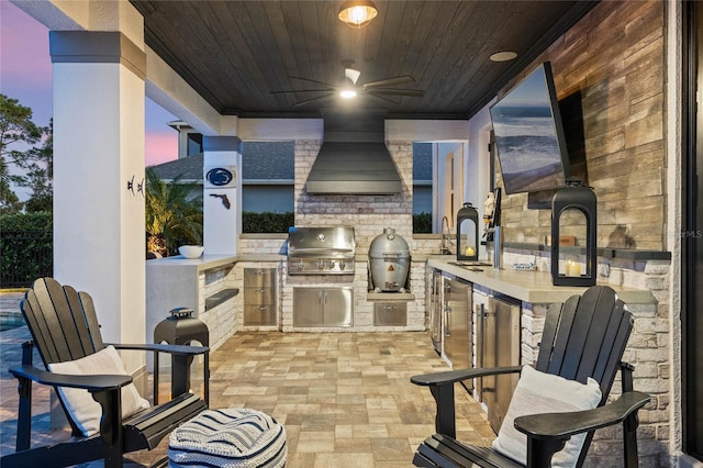 patio terrace at dusk featuring exterior kitchen, ceiling fan, sink, and grilling area