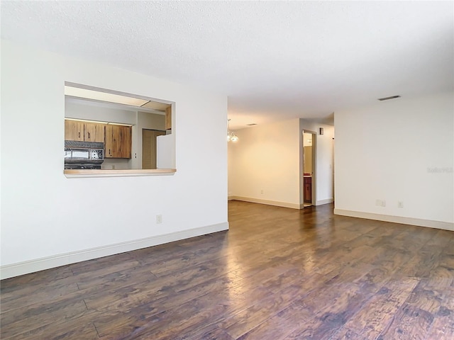 spare room featuring dark wood-type flooring and a textured ceiling