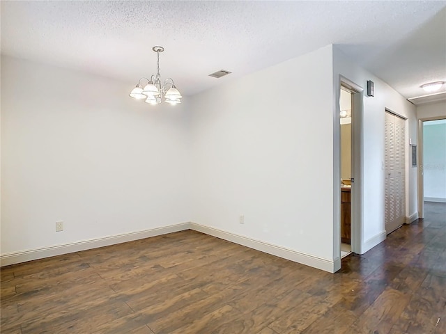 unfurnished room with dark hardwood / wood-style floors, an inviting chandelier, and a textured ceiling