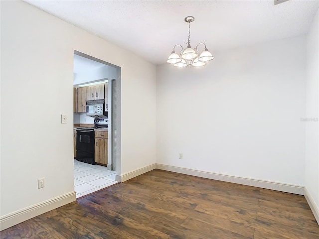 empty room with a notable chandelier and light hardwood / wood-style flooring