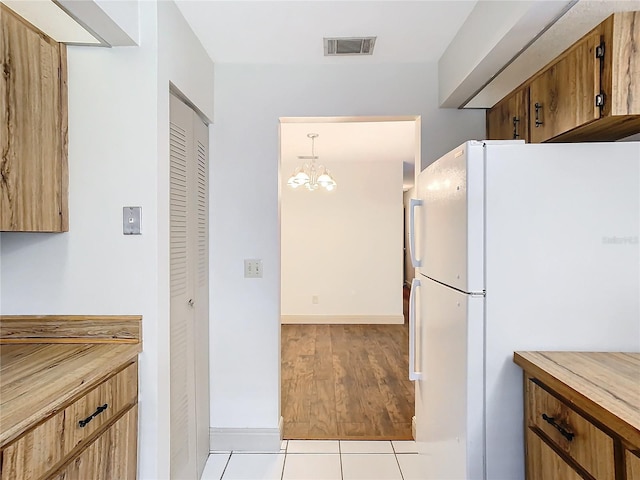 kitchen featuring hanging light fixtures, white fridge, and light tile patterned floors