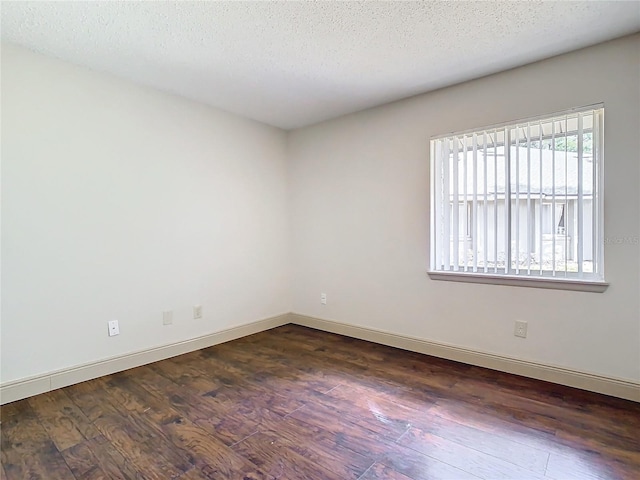 empty room with dark hardwood / wood-style floors and a textured ceiling