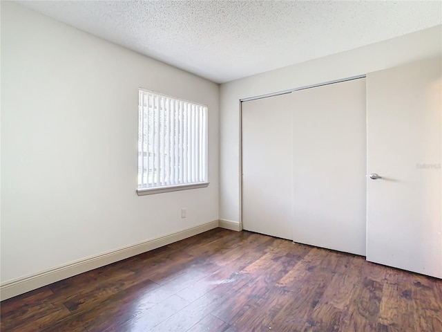 unfurnished bedroom featuring a closet, dark hardwood / wood-style floors, and a textured ceiling