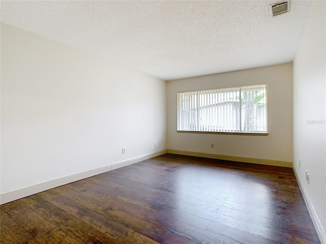 spare room featuring a textured ceiling and dark hardwood / wood-style flooring