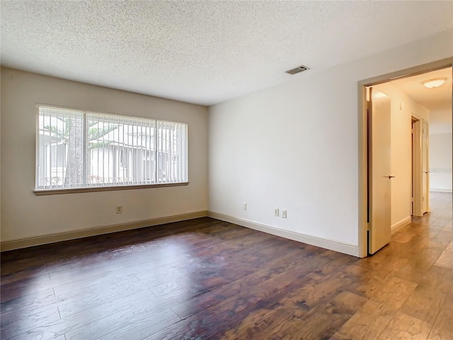 empty room with dark wood-type flooring and a textured ceiling