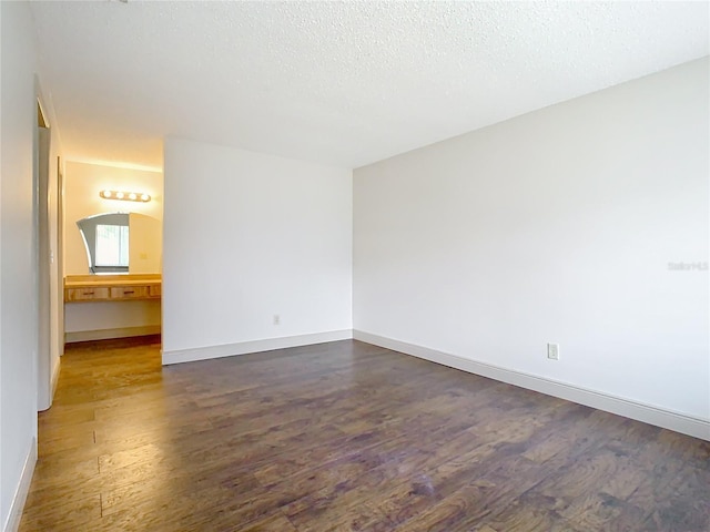 empty room with dark wood-type flooring and a textured ceiling