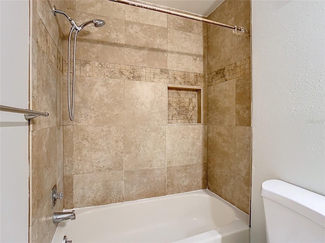 bathroom with tiled shower / bath combo and toilet