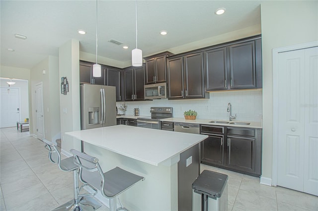 kitchen featuring sink, decorative light fixtures, a center island, a kitchen breakfast bar, and stainless steel appliances