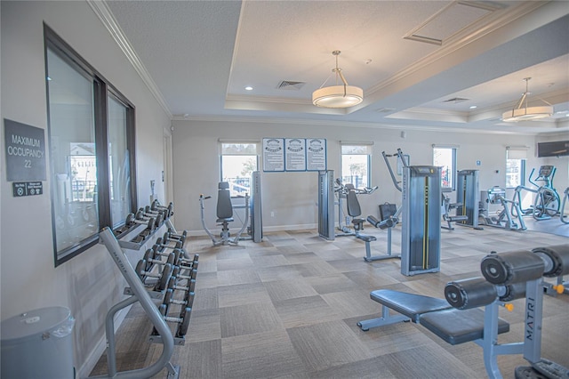 gym featuring light colored carpet, ornamental molding, a raised ceiling, and a textured ceiling