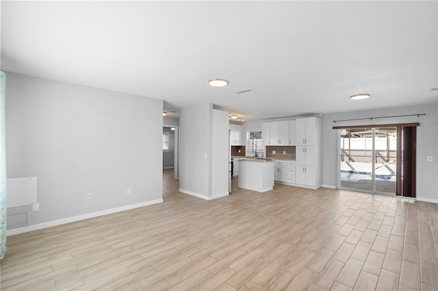 unfurnished living room with sink and light hardwood / wood-style floors