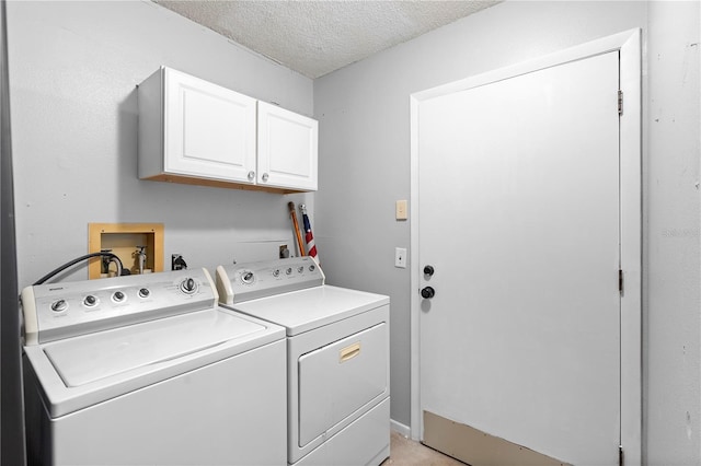 clothes washing area featuring cabinets, washing machine and dryer, and a textured ceiling