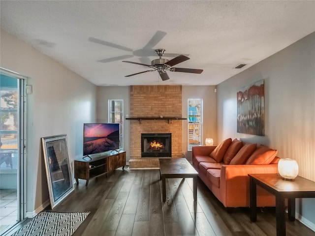 living room featuring plenty of natural light, a textured ceiling, dark hardwood / wood-style flooring, and a fireplace