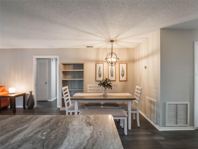 dining room featuring dark hardwood / wood-style flooring, a textured ceiling, and a chandelier