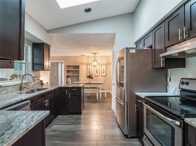 kitchen with sink, hardwood / wood-style flooring, stainless steel appliances, light stone counters, and decorative light fixtures