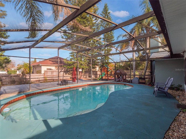 view of pool with a patio area, a playground, and glass enclosure