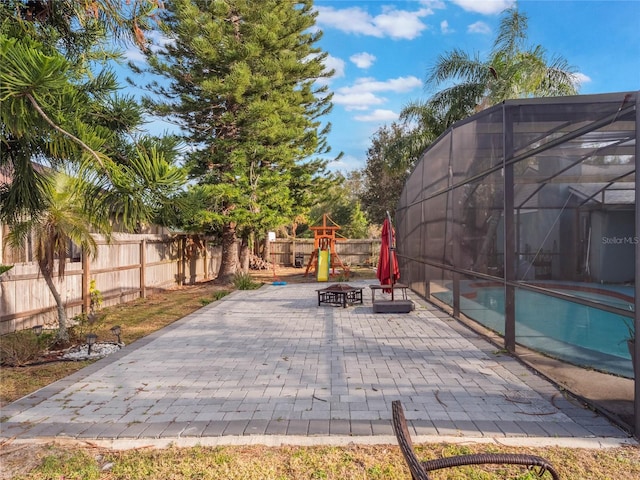 view of patio featuring a fenced in pool, a playground, and glass enclosure