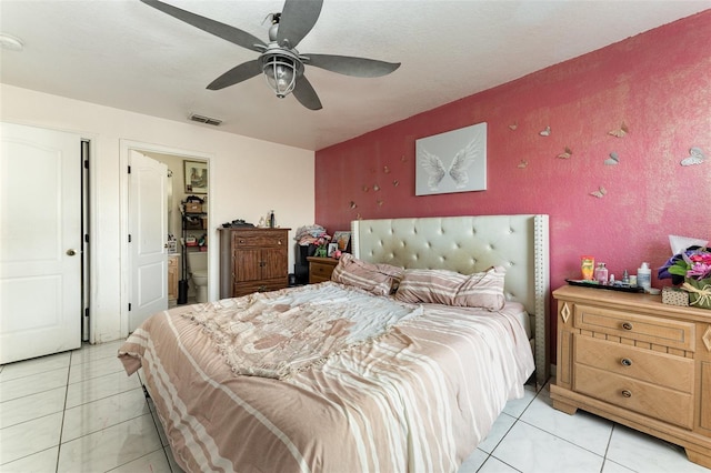 bedroom featuring connected bathroom, light tile patterned floors, and ceiling fan