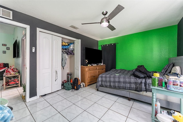 tiled bedroom with ceiling fan and a closet