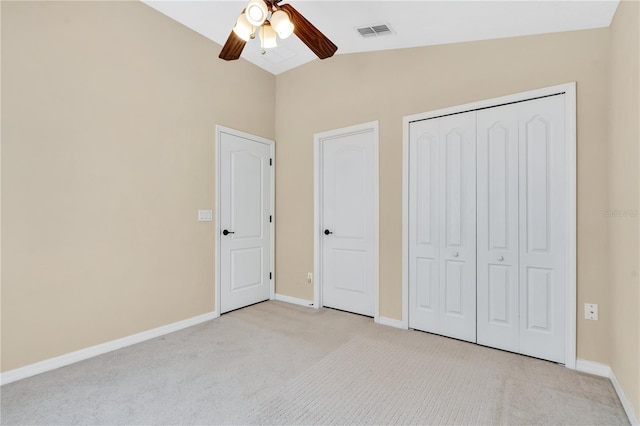 unfurnished bedroom with ceiling fan, a closet, vaulted ceiling, and light carpet