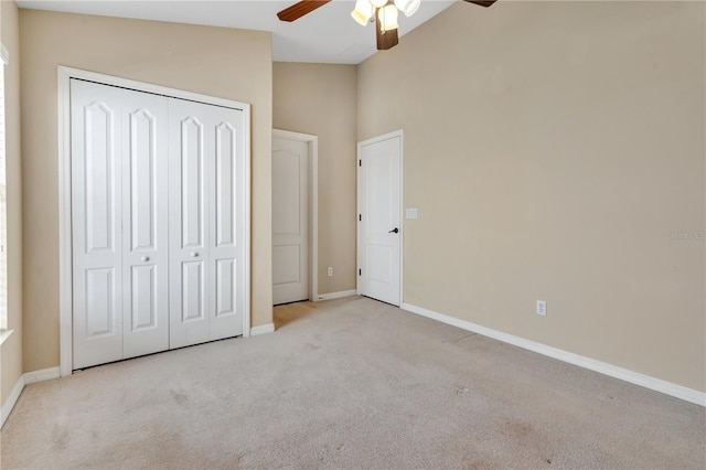 unfurnished bedroom featuring ceiling fan, light colored carpet, vaulted ceiling, and a closet