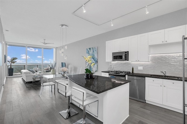 kitchen featuring sink, white cabinetry, decorative light fixtures, a center island, and stainless steel appliances