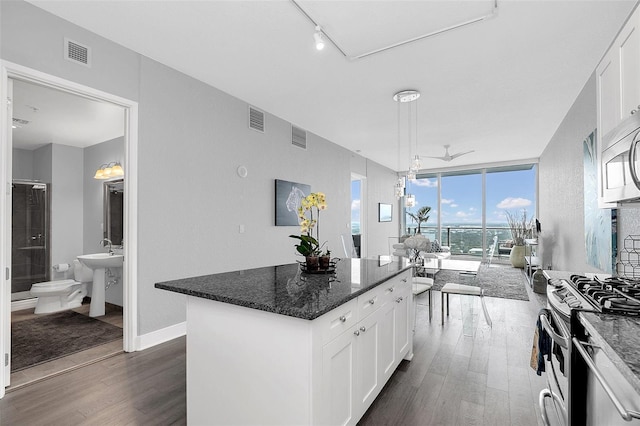 kitchen with a kitchen island, dark hardwood / wood-style floors, white cabinets, and dark stone counters