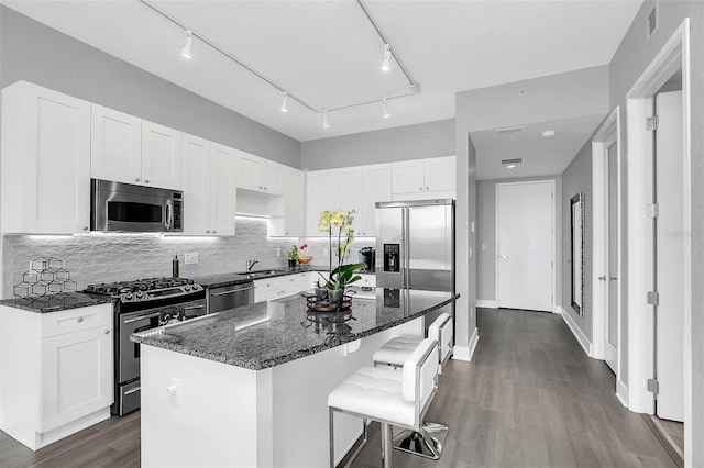 kitchen with white cabinetry, appliances with stainless steel finishes, a kitchen breakfast bar, and a center island