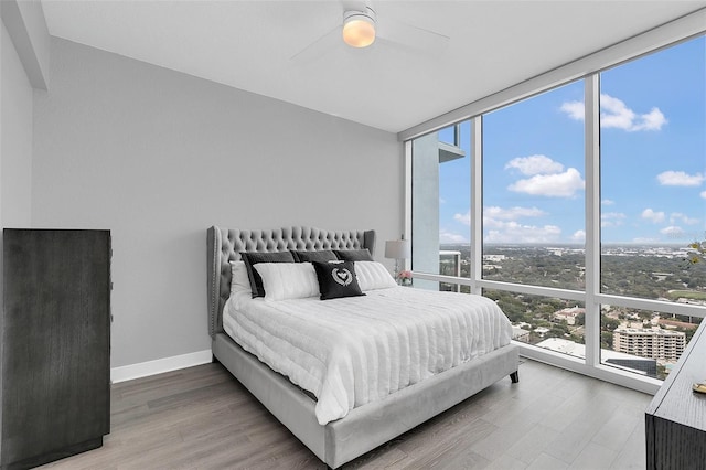 bedroom with hardwood / wood-style floors, a wall of windows, and ceiling fan