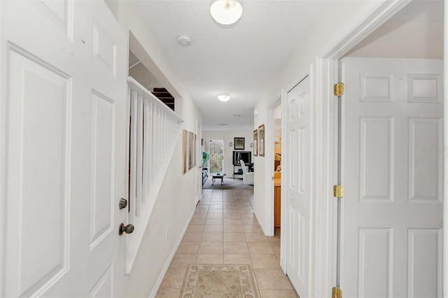 hallway with light tile patterned flooring and a textured ceiling