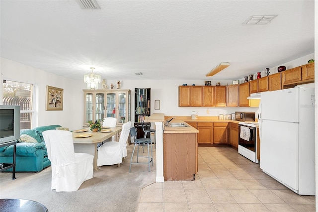 kitchen with sink, white appliances, light tile patterned floors, hanging light fixtures, and a kitchen island