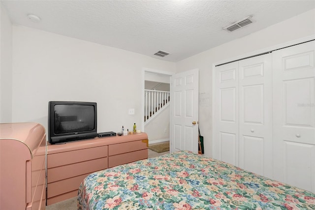 carpeted bedroom featuring a closet and a textured ceiling