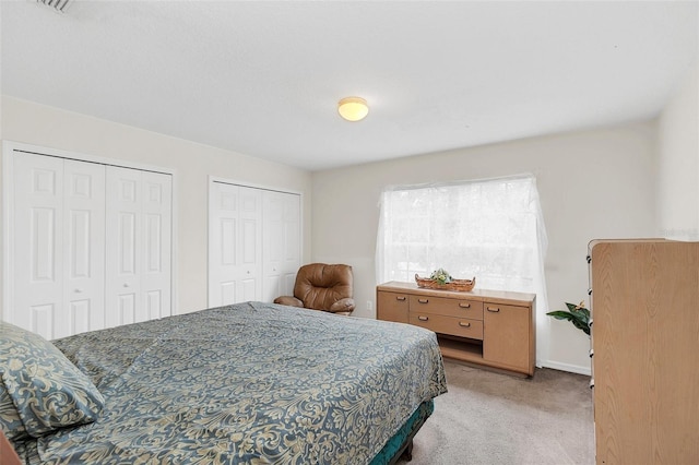 bedroom with light carpet and two closets