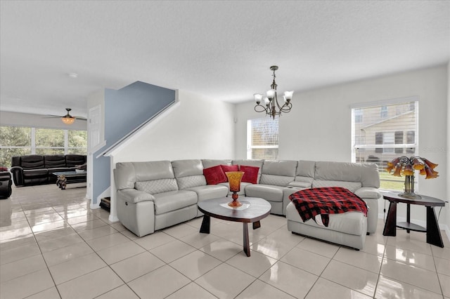 tiled living room with ceiling fan with notable chandelier and a textured ceiling