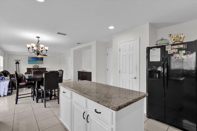 kitchen featuring a center island, a notable chandelier, white cabinets, light tile patterned flooring, and black refrigerator with ice dispenser