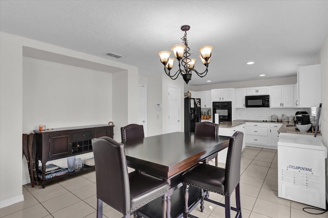 tiled dining room featuring a notable chandelier and a textured ceiling