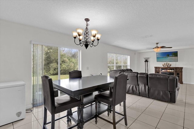 dining space featuring ceiling fan with notable chandelier, a textured ceiling, and light tile patterned floors