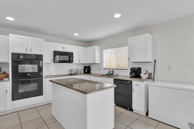 kitchen with a kitchen island, white cabinetry, sink, light stone counters, and black appliances