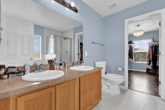 bathroom with tile patterned flooring, vanity, walk in shower, a notable chandelier, and toilet