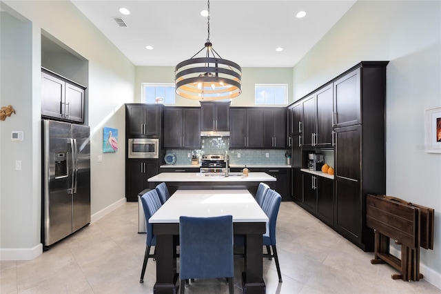 kitchen featuring pendant lighting, sink, appliances with stainless steel finishes, backsplash, and a center island with sink