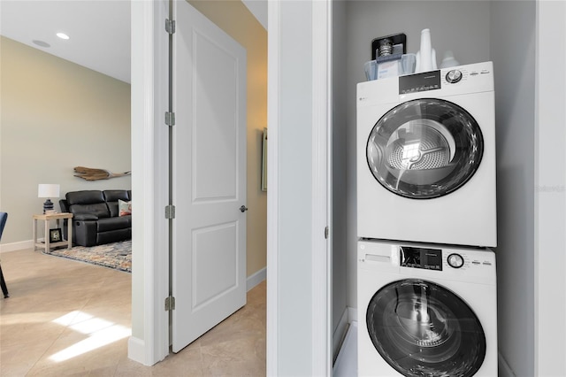 laundry area with light tile patterned floors and stacked washing maching and dryer