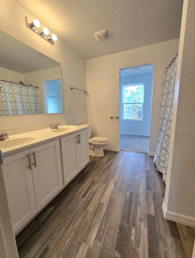 bathroom with hardwood / wood-style flooring, vanity, toilet, and a textured ceiling